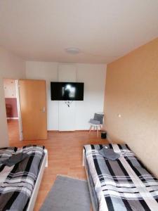 1 dormitorio con 2 camas y TV de pantalla plana en schöne Ferienwohnung über den Dächern von Plauen, en Plauen