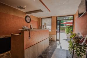 a restaurant with a counter and a clock on the wall at Hotel Petra in La Romanina