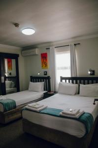 two beds sitting in a room with a window at Towers Lodge in Boksburg