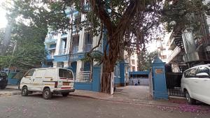 una furgoneta blanca estacionada frente a un edificio azul en Bentleys Hotel en Bombay