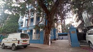 una furgoneta blanca estacionada frente a un edificio azul en Bentleys Hotel, en Bombay