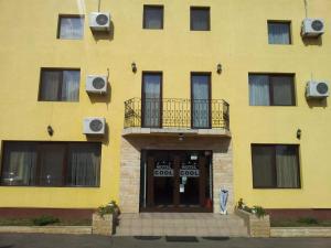 a yellow building with a balcony and a door at MOTEL COOL in Bărcăneşti