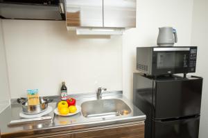 a small kitchen with a sink and a microwave at BON Kyoto Station in Kyoto