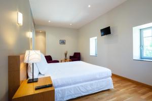 a bedroom with a white bed and a desk with a lamp at L'Ortensia in Saint-Gervais-sur-Mare