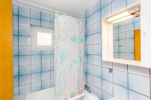 - une salle de bains carrelée de bleu avec rideau de douche dans l'établissement Villa Bind, à Cavtat