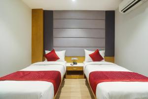 two beds in a hotel room with red pillows at Hotel Bricks, Karol Bagh, New Delhi in New Delhi