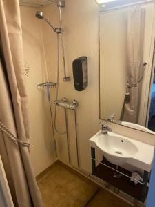 uma casa de banho com um lavatório e um chuveiro com um espelho. em Hotellilaiva Wuoksi em Kuopio