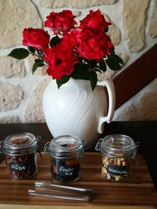 un jarrón blanco con flores rojas en una mesa en Gästehaus Nord-West 1700 - Doppelzimmer Ozean en Steenfeld