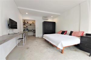 sypialnia z łóżkiem, biurkiem i telewizorem w obiekcie Margarita Surf Hostel w mieście Canggu