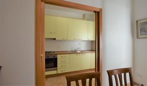 La cuisine est équipée de placards blancs, d'un lavabo et d'un miroir. dans l'établissement Primavera, à Marina di Campo