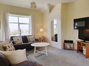 Una sala de estar con un sofá y un televisor. en BRYN GORS-3 BED-FIRST FLOOR APT- YARDS FROM BEACH, en Trearddur