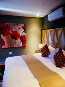 a bedroom with a large bed with red flowers on the wall at Thavhani boutique hotel in Thohoyandou