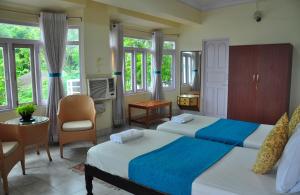 a bedroom with two beds and a table and chairs at Kokari Guesthouse in Port Blair