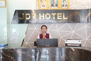 eine Frau, die vor einem Schreibtisch mit einem Laptop steht in der Unterkunft Joy Hotel in Phnom Penh