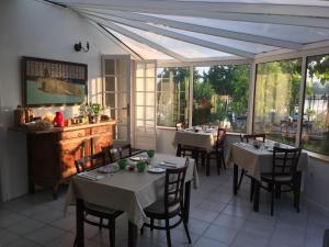 a dining room with tables and chairs and windows at La Houache Chambres d'Hôtes in Le Pellerin