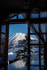 una ventana con vistas a una montaña cubierta de nieve en Pension Berg, en Niseko