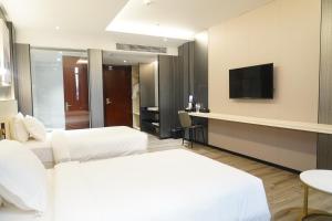 a hotel room with two beds and a flat screen tv at Joy Hotel in Phnom Penh