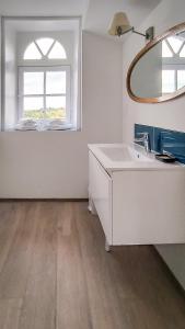 W białej łazience znajduje się umywalka i lustro. w obiekcie La Houache Chambres d'Hôtes w mieście Le Pellerin