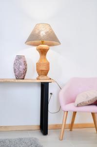 Couloumé-Mondébat的住宿－Château Boussas，一张桌子上的一盏灯,旁边是一张粉红色的椅子