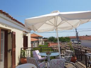 a table and chairs under an umbrella on a balcony at Kalliopi House For 6 - Keros Beach in Kalliópi