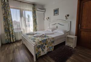 a bedroom with a white bed and a window at Pensiunea Geostar in Curtea de Argeş