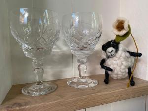 two wine glasses and a stuffed animal sitting on a shelf at Chez Maurice Luxury Shepherds Hut with Bath and Hot Tub in Kelling