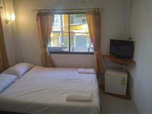 a small bedroom with a bed and a window at Kamala bay inn in Kamala Beach