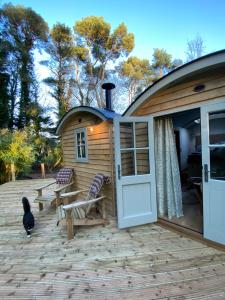 a cabin with a door open on a patio at Chez Maurice Luxury Shepherds Hut with Bath and Hot Tub in Kelling