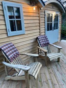 two chairs sitting on a porch of a house at Chez Maurice Luxury Shepherds Hut with Bath and Hot Tub in Kelling +11 photos