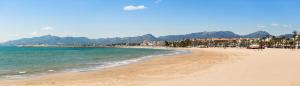 a beach with the ocean and mountains in the background at apartamento Kottmann in Cambrils