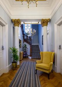 un couloir avec des colonnes, une chaise jaune et des escaliers dans l'établissement The Clarendon, à Dundee