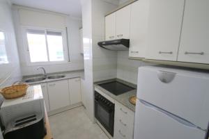a white kitchen with a sink and a refrigerator at Apartamento Villa Adriana 205 in Miami Platja
