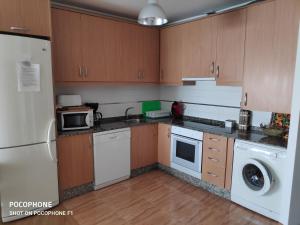a kitchen with wooden cabinets and a white refrigerator at La Mariña in Ribadeo