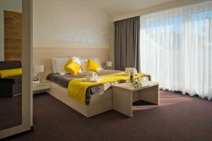 a hotel room with a bed with yellow sheets and a window at Hotel Bor in Krk