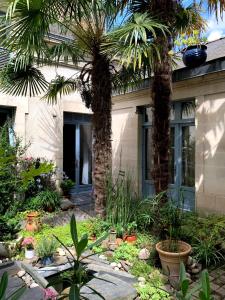 a garden with palm trees and plants in front of a house at Les Pénates de Loire in Ancenis