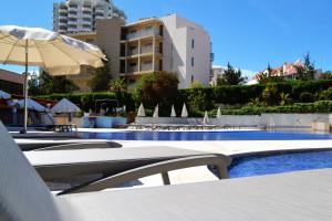 une piscine avec des chaises et un parasol et un bâtiment dans l'établissement S&S Apartment, à Portimão