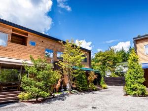 an exterior view of a building with trees at Kawaguchiko Villa FJ Resort in Fujikawaguchiko