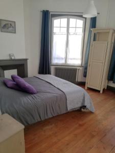 a bedroom with a bed with purple pillows and a window at Halte en B in Noyelles-sur-Mer