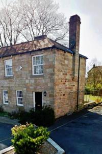 a brick house with a chimney on top of it at Cheerful 2-bed cottage with 2 free parking Leeds in Meanwood