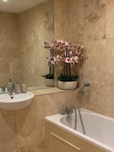 a bathroom with a sink and a bath tub with flowers at Cheerful 2-bed cottage with 2 free parking Leeds in Meanwood