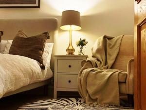 a bedroom with a bed and a lamp and a chair at Cheerful 2-bed cottage with 2 free parking Leeds in Meanwood