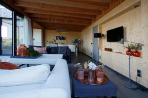 uma sala de estar com sofás brancos e uma televisão em Dunes of Egmond em Egmond-Binnen