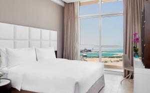 A bed or beds in a room at Staybridge Suites - Doha Lusail by IHG
