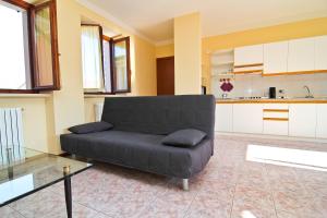 un soggiorno con divano nero e una cucina di Residence Corte del Bosco a Garda