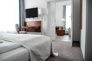 a bedroom with a bed and a television on the wall at Heerens Hotel in Emden
