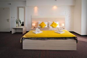 a bedroom with a large yellow bed with towels on it at Hotel Bor in Krk