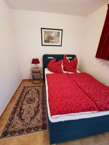 1 dormitorio con cama azul con almohadas rojas y alfombra en ​Gästehaus Frans-Jozef, en Mönichkirchen