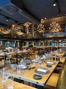 a restaurant with wooden tables and chairs and chandeliers at Autohalle Hotel in Andelfingen