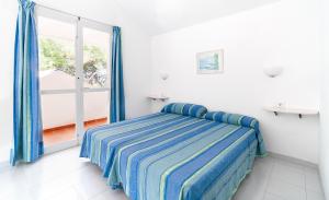 una camera con un letto con una coperta a righe blu di Club Ciudadela a Son Xoriguer
