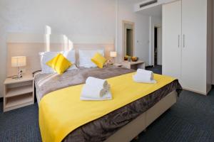 a bedroom with a large yellow bed with towels on it at Hotel Bor in Krk